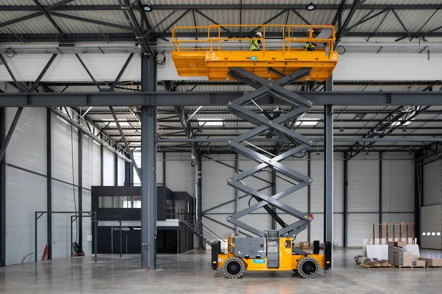 Nacelle élévatrice à ciseaux électrique en travail intérieur dans un hangar