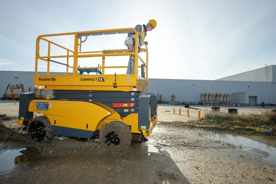 Nacelle à ciseaux thermique 4x4 sur terrain de chantier non stabilisé